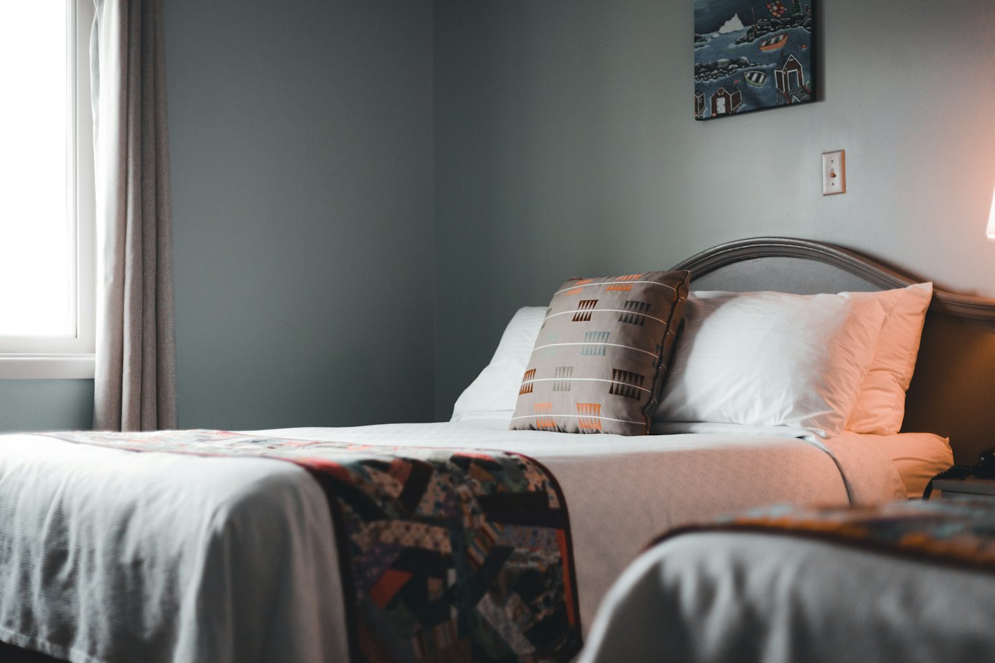 Two hotel beds with white linens and decorative pillows.