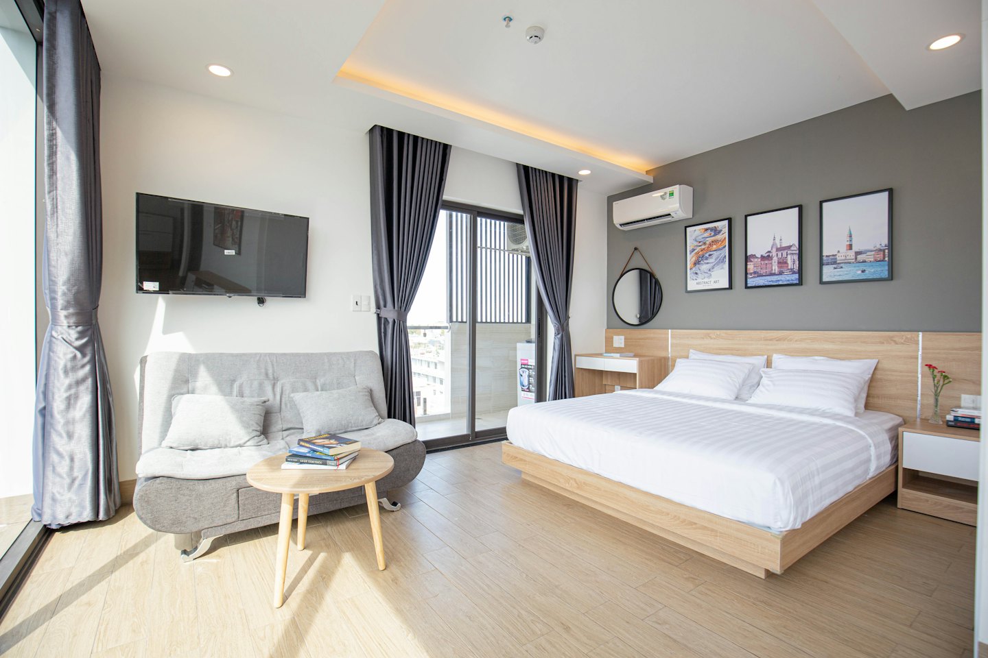 Modern studio apartment with a bed, grey sofa, and coffee table.